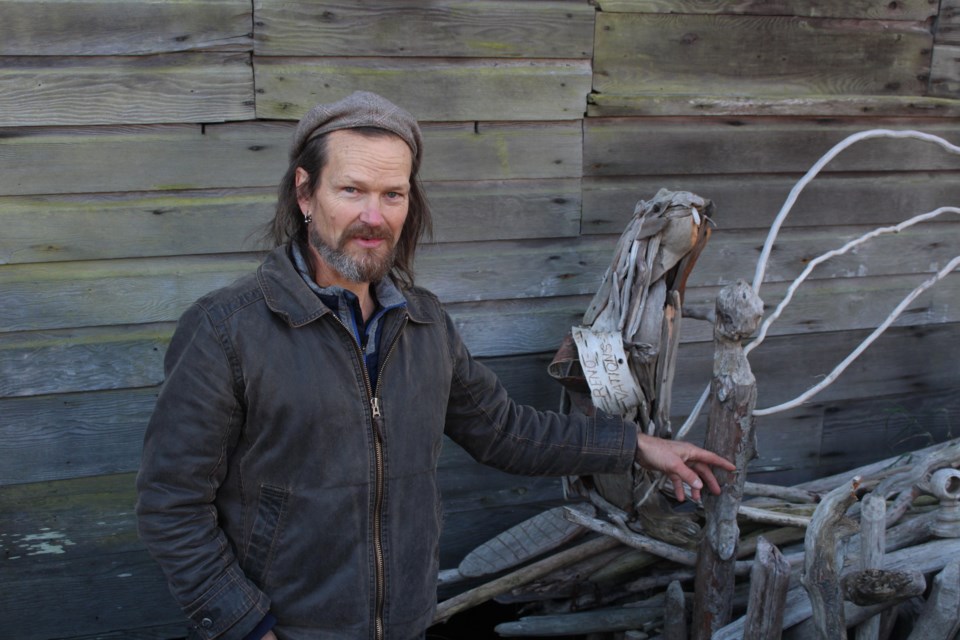 Artist Glen Andersen points out a pillar in his sculpture that looks like a sculpture of a human head created by a beaver.