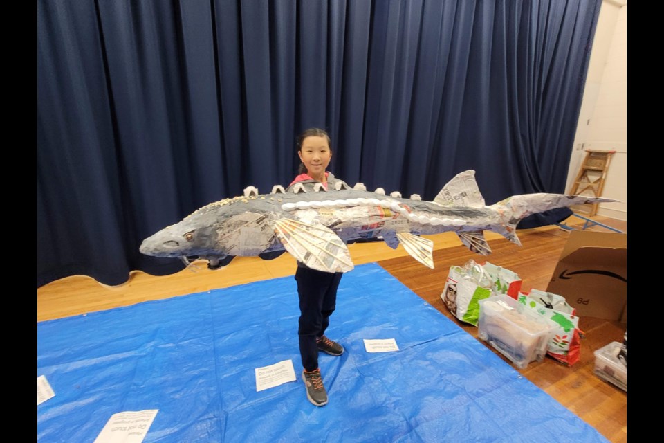 Richmond student Opal Chen with a six-foot paper mache sturgeon.