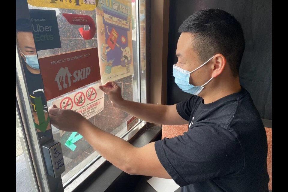 A restaurant staff was putting up the correct smoking sign handed out by Aaron Leung. 