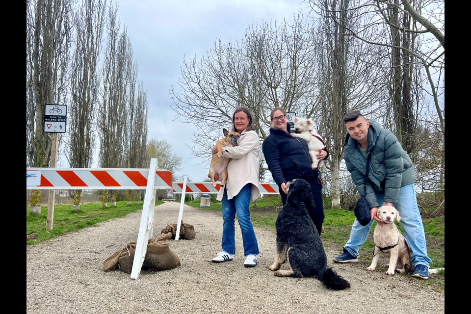 Julie Halsey-Brandt and her French bulldog posing with Karen Yamada, her son and their dogs near the path where a cyclist hit Halsey-Brandt’s dog.
