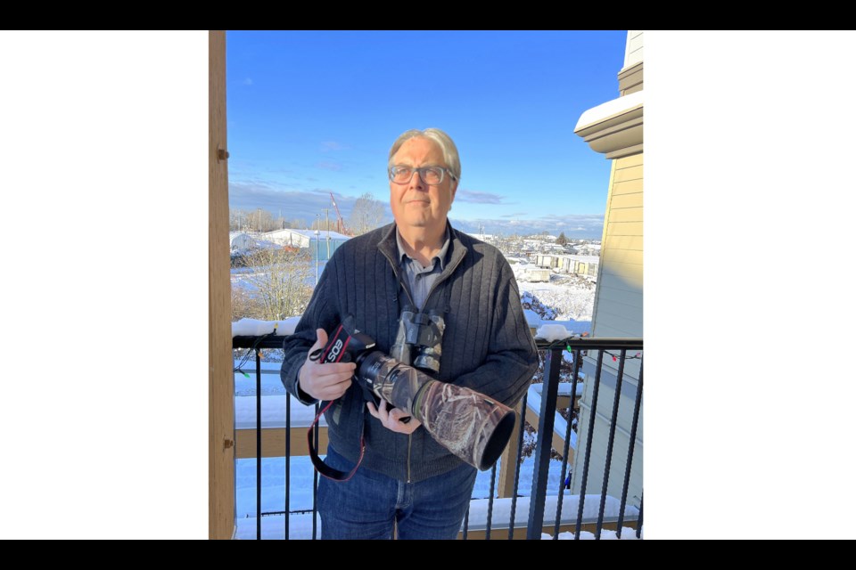 Geoff McDonell posing with his retirement present: a Canon digital camera with a telephoto lens.