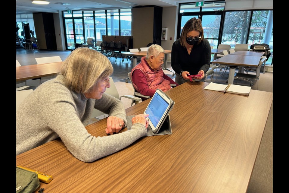 Nayeli Garcia (right), account executive at Richmond News, working with seniors on accessing online news.