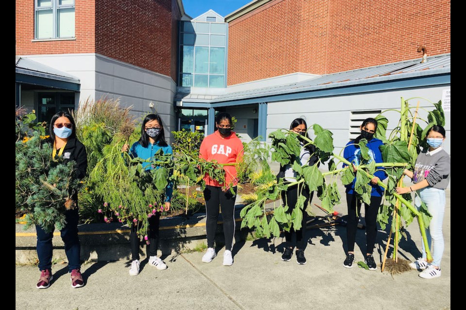 Members of the Cambie “Ecosavers” and sponsor teacher Mandy Yam hold up some of the many plants recently destroyed by vandals. 