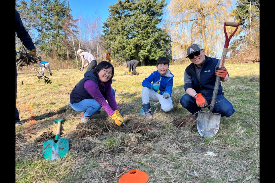 Adrian Choi, joined here by his mom and dad, found the biggest root at a recent invasive species eradication event in Richmond.