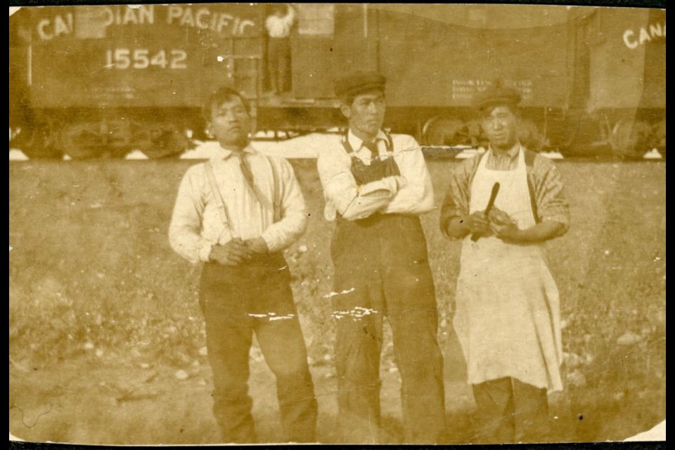 Eikichi Harada (centre) and two other men posing in front of CPR train cars. Photo taken between 1908 and 1928.  