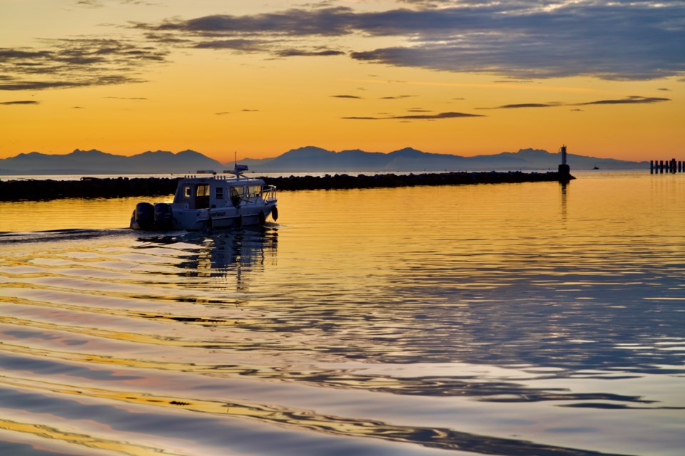 A fishing boat cruising into the sunset on the Fraser River.
