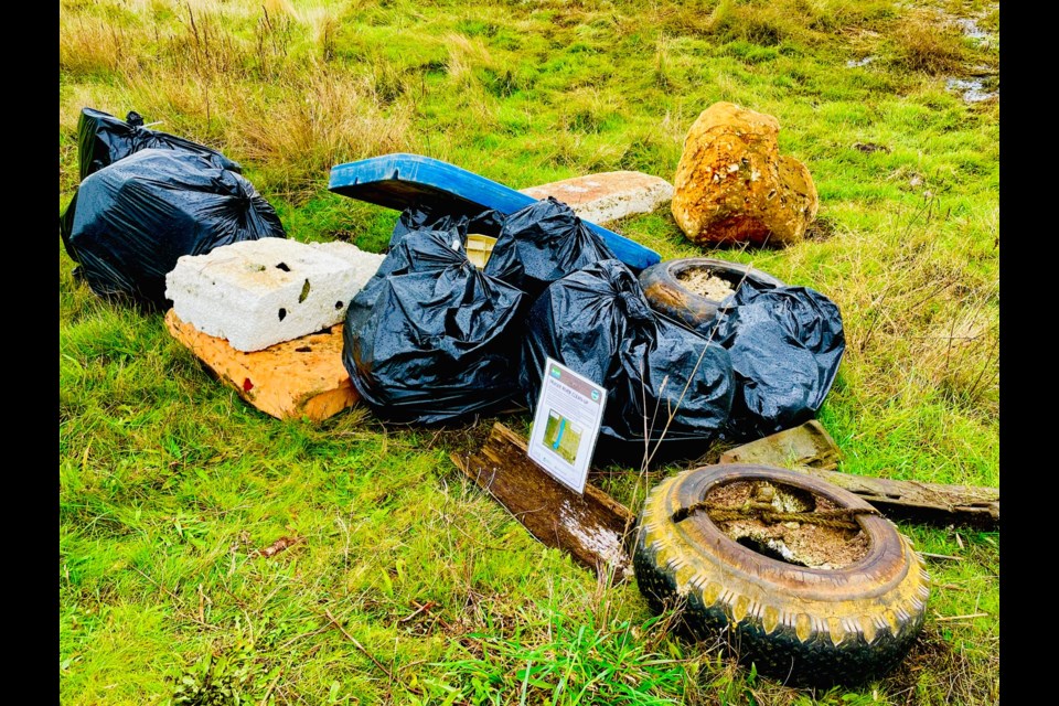 A pile of debris with a sign letting people know about the cleanup. Debris is removed at the end of each week and taking to a recycling facility.