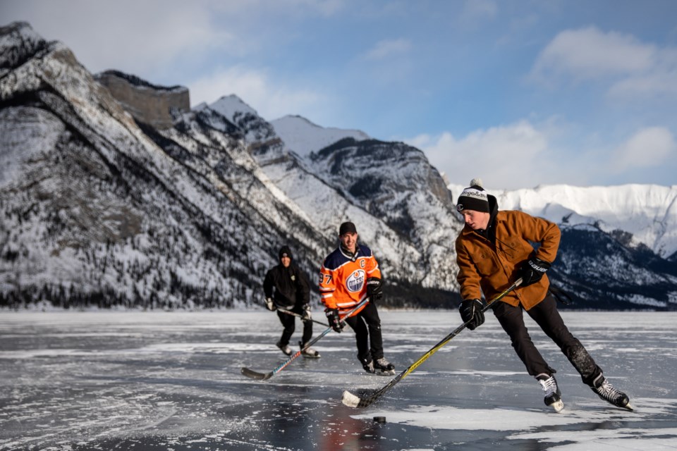 Hans Vivian, right, Ryan Hunter and James Johnston play a game of keep away on Lake Minnewanka on Thursday (Jan. 2). EVAN BUHLER RMO PHOTO