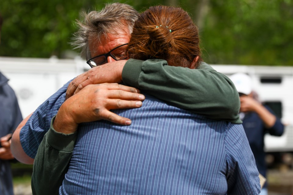 Margaret and Ralph Anderson embrace each other as neighbours help pack up the main floor of their house in Exshaw on Friday (June 5). The family is clearing out the main floor of their house after noticing the floor starting to buckle due to the rising ground water causing flooding in the small hamlet. EVAN BUHLER RMO PHOTO⁠