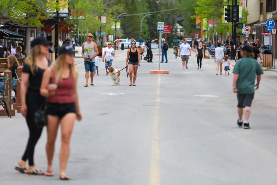 Pedestrians walk down the middle of Main Street in Canmore on Friday (June 12). The Town of Canmore closed Main Street to vehicle traffic help ease social distancing between pedestrians because of COVID-19. EVAN BUHLER RMO PHOTO⁠