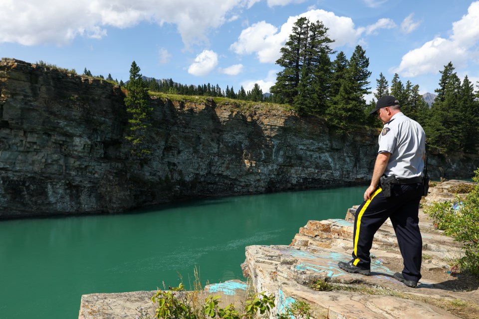 Cochrane RCMP Cpl. Troy Savinkoff looks out over a cliff along the Bow River where the suspected drowning victim Blessing Paul, 16, disappeared near the Seebe Dam, on Tuesday (Aug. 11). EVAN BUHLER RMO PHOTO