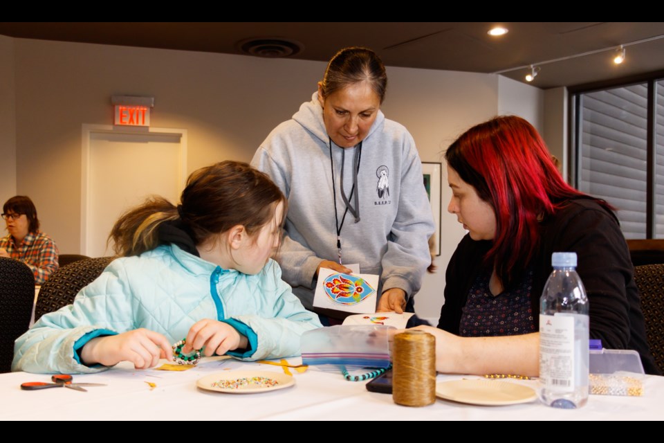 Artist teacher Samantha Smalleyes, centre, shows guests Averlee, 9, left and Trudy Laurence an example of her beading at the Banff Centre Family Winter Arts Festival on Sunday, Feb. 16, 2020. CHELSEA KEMP RMO PHOTO