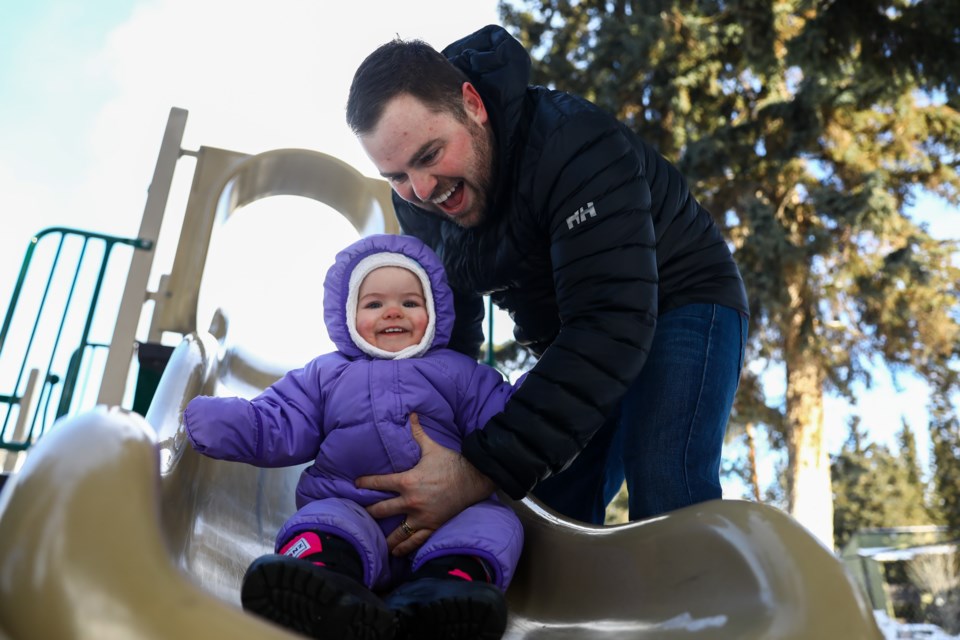 Dean Cooper holds on to his daughter Hazel Grace as she enjoys sliding at the Rotary Park playground in Banff on Tuesday (Feb. 16). EVAN BUHLER RMO PHOTO
