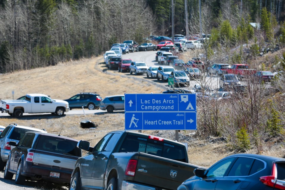 Several dozen cars park along the Lac des Arcs highway exit and along the road to the Heart Creek trail head parking lot on Saturday (April 17). The parking lot was full. EVAN BUHLER RMO PHOTO