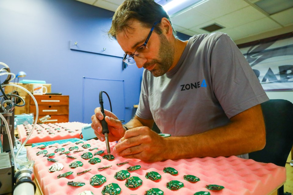 Dan Roycroft, founder of Zone4, solders one of the chips found in their timing devices on Tuesday (July 20). EVAN BUHLER RMO PHOTO