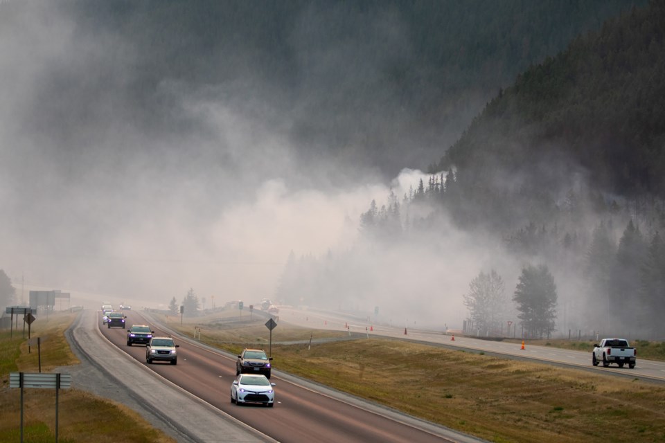 Vehicles on the Trans-Canada Highway drive past a wildfire at the base of Pigeon Mountain near Dead Man's Flats, about four kilometres east of Canmore in 2021. RMO FILE PHOTO