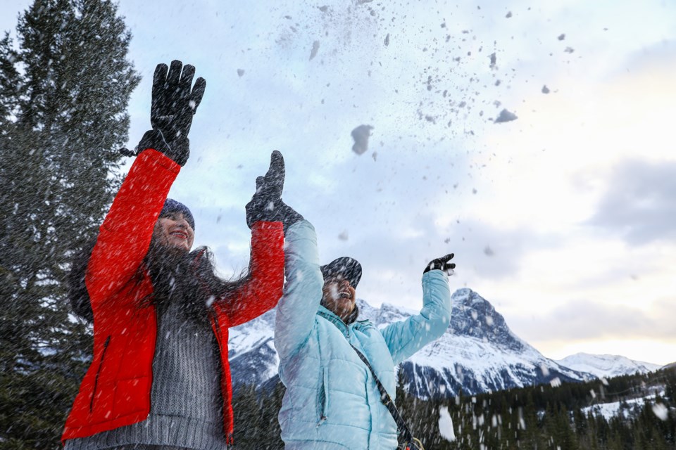 Jasleen Kaur Oberoi, left, and Mansimran Kaur throw snow into the air for a picture near Engine Bridge in Canmore on Tuesday (Nov. 16). EVAN BUHLER RMO PHOTO