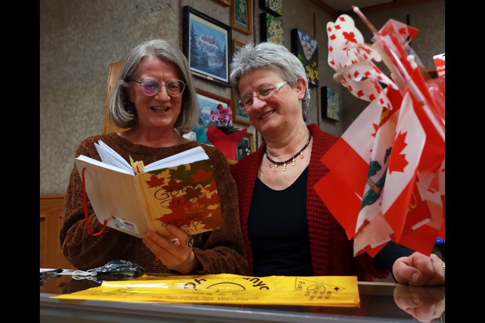 Sisters Maya Wojnarowska, left, and Ewa Wojnarowska, look at a signed book from longtime customers on Thursday (Feb. 18) in Goro Canyon Smoke and Gift Shop in the Banff Park Lodge. The two sisters, along with a third Roma Osicki, have been involved with the well known store for several decades.

GREG COLGAN RMO PHOTO