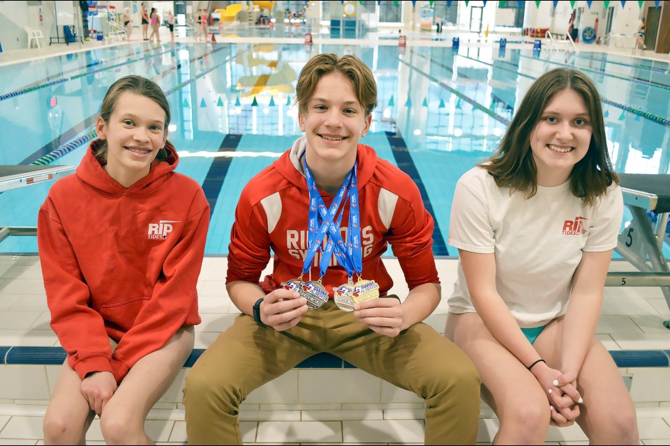 Bow Valley Riptides swimmers Chloe Kestle, left, Benedek Purnhauser, and Jaime Lakusta sit poolside at Elevation Place in Canmore. The trio competed at the 2022 Provincial Championships in March, winning individual and team awards. JORDAN SMALL RMO PHOTO
