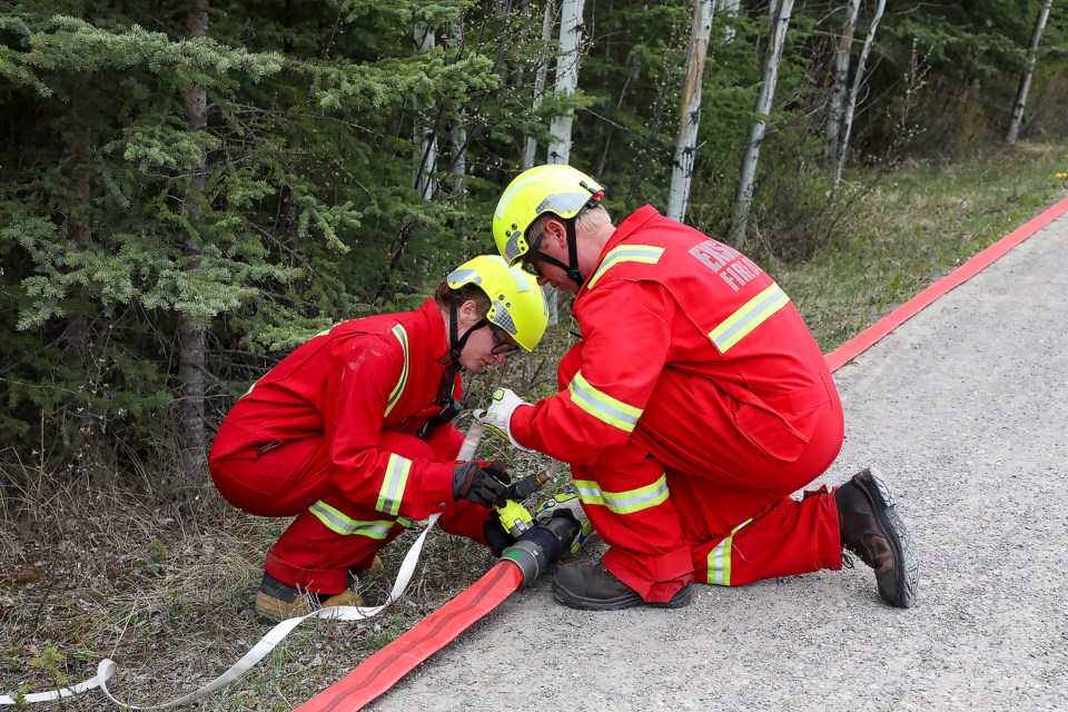 An Exshaw Fire-Rescue crew checks hose connections for the sprinkler system along the trail behind Larch Avenue on Saturday (June 4). The sprinkler systems aim to protect from a potential wildfire during the Georgetown wildfire exercise.

JUNGMIN HAM RMO PHOTO