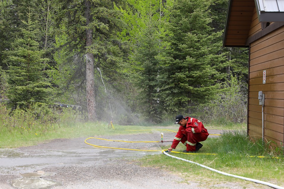 Nakoda Fire Department firefighter Japheth Rollinmud checks a sprinkler system near Larch Avenue and Fairholme Drive on Saturday (June 4). The sprinkler systems are setup to protect from a potential wildfire during the mock Georgetown wildfire exercise.

JUNGMIN HAM RMO PHOTO