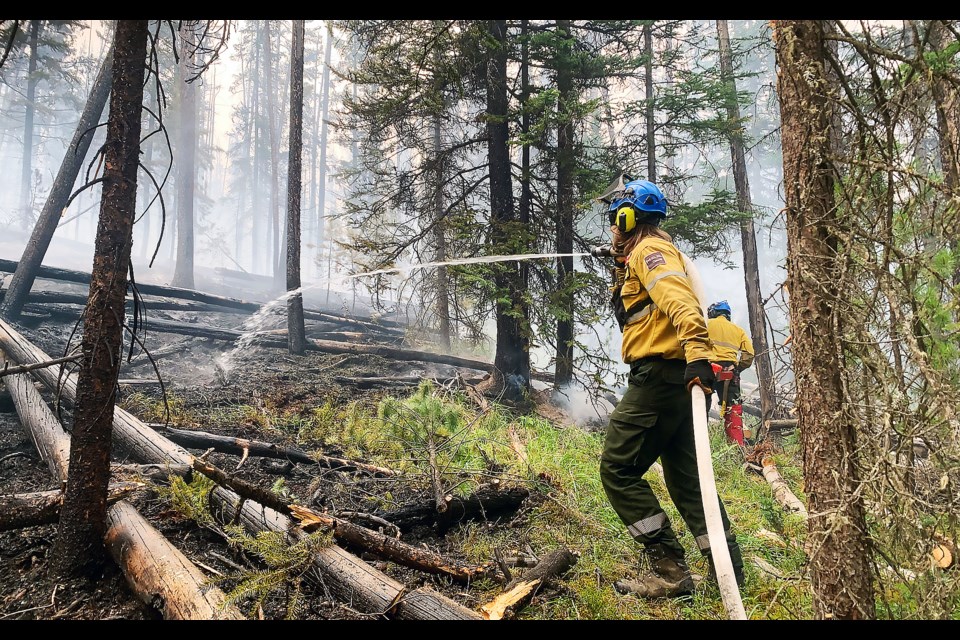 A Parks Canada employee holds a hose that's spraying water on the ground during the prescribed fire by Parks Canada in the Alexandra Valley from Aug. 18-23, 2022.

PHOTO COURTESY OF PARKS CANADA