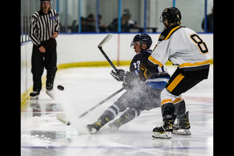 Kyle Young, left, of the Canmore Eagles battles with an Olds Grizzlys player for possession of a loose puck in the corner during the Eagles exhibition game at the Canmore Recreation Centre on Friday (Sept. 9). JUNGMIN HAM RMO PHOTO