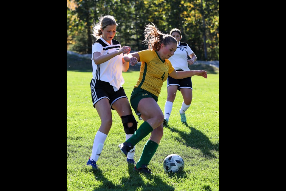 Aria Grandi (No. 4) of the Canmore Collegiate girls soccer team and the Holy Trinity Knights player fight for the ball during the game at Millennium Park in Canmore on Tuesday (Sept. 27). The Canmore Collegiate girls soccer team defeated the Holy Trinity Knights 6-2. JUNGMIN HAM RMO PHOTO