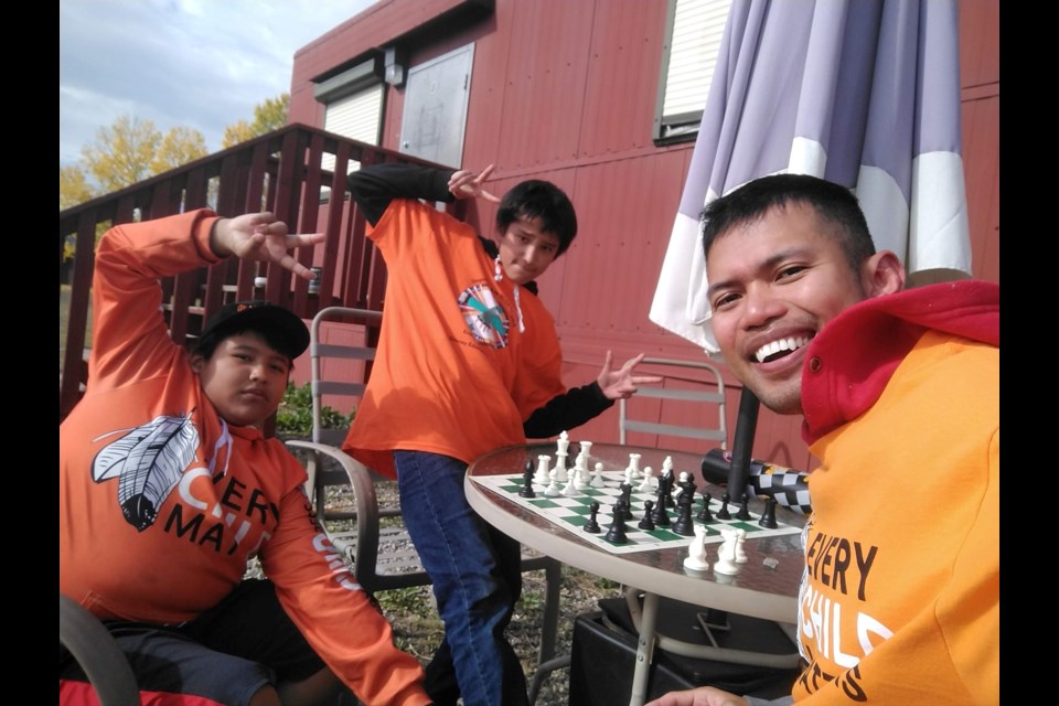 Jyn San Miguel, right, plays a chess round with Mînî Thnî residents Sage Dixon Rider, left, and Kaleb Powderface, middle, after the Sept. 30 Every Child Matters Walk.

PHOTO COURTESY OF JYN SAN MIGUEL
