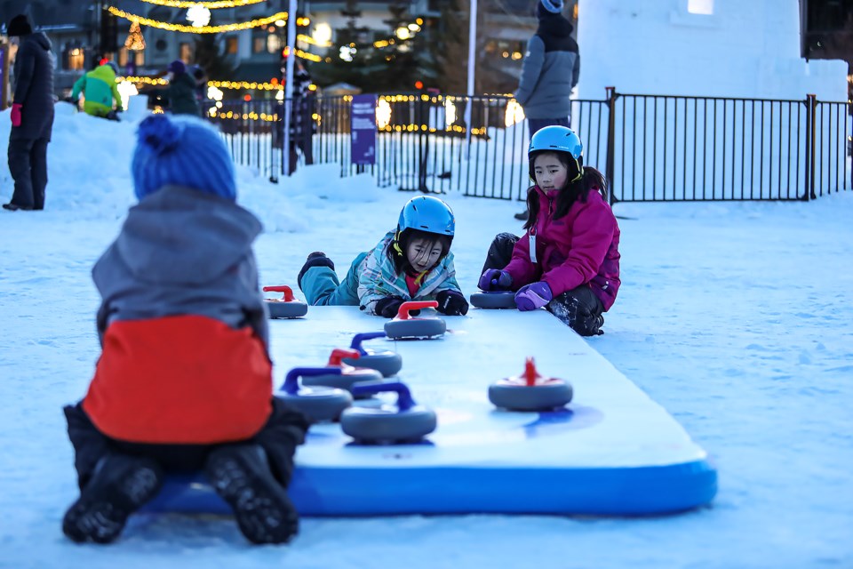 Asahi Watanabe, right, and Suzuran Watanabe, centre, play curling in a play area at the Snow Days Winter Festival on Thursday (Jan. 19). SnowDays Winter Festival runs Jan.18-29. JUNGMIN HAM RMO PHOTO