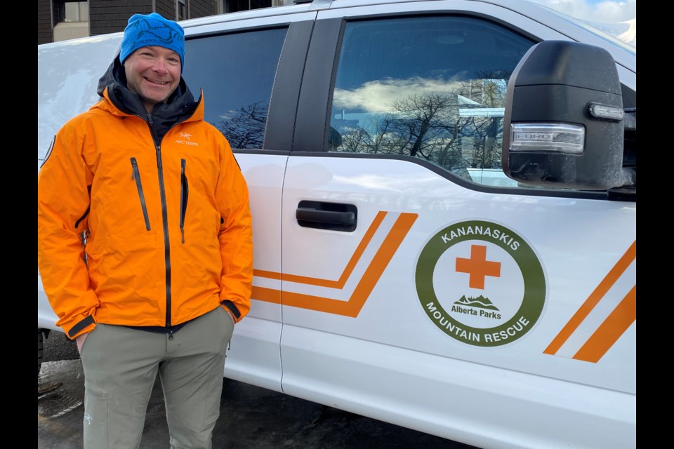 Mountain rescue specialist Matt Mueller of the formerly known Kananaskis Country Public Safety program, is pictured beside a logo with the organization's new name, Kananaskis Mountain Rescue. 

SUBMITTED PHOTO