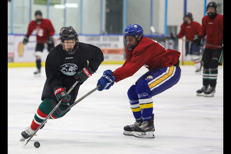 Sasha Plourde, left, and Christopher Ugbaja battle for the puck during the Canmore Eagles spring camp at the Canmore Recreation Centre on Friday (April 14). JUNGMIN HAM RMO PHOTO 