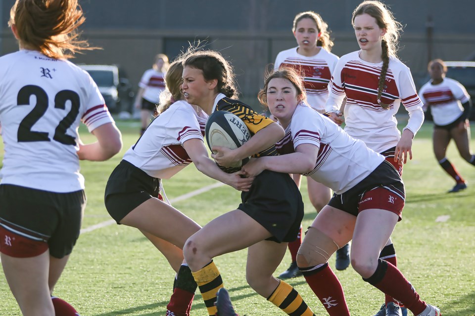 Banff Bear Maggie O'Connor fights off two Rundle Cobras during rugby action at Rundle College in Calgary on Thursday (April 27). The Bears beat the Cobras 35-17. JUNGMIN HAM RMO PHOTO 