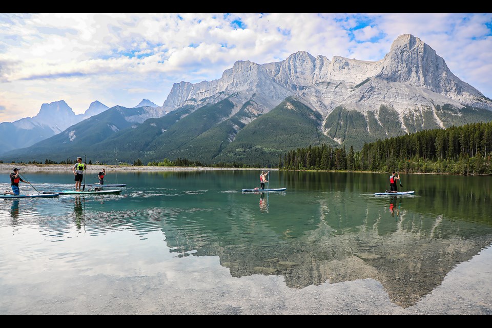 Participants enjoy paddle boarding at stand-up paddle boarding lesson and ride hosted by the Canmore Youth Network and guided by the Bow Valley SUP and surf team at Rundle Forebay Reservoir in Canmore on Thursday (July 6). JUNGMIN HAM RMO PHOTO
