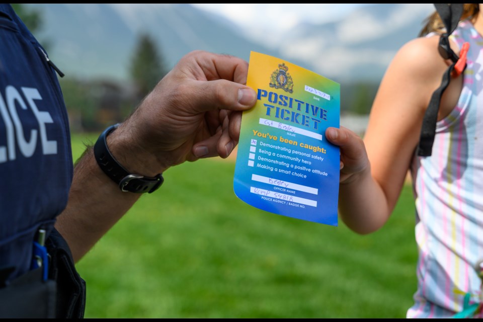 Cst. Chris Begley holds a positive ticket with Sawyer Corbett, 6, in Canmore on Monday (July 17). The positive ticketing program runs from July to September which helps promote public safety and creates positive interactions between law enforcement and the community. MATTHEW THOMPSON RMO PHOTO