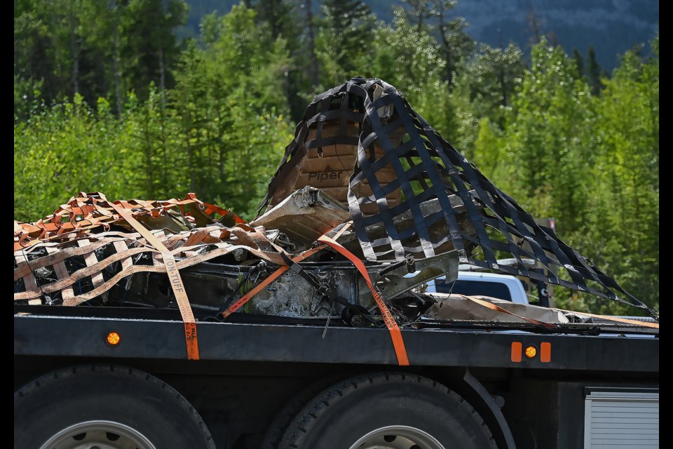 A flat bed truck halls debris from a crashed airplane after a helicopter flew it out of the crash site near Kananaskis Village on Saturday (July 29). The word "Piper" can be seen on the debris referring to the model of the plane, a Piper PA32. MATTHEW THOMPSON RMO PHOTO