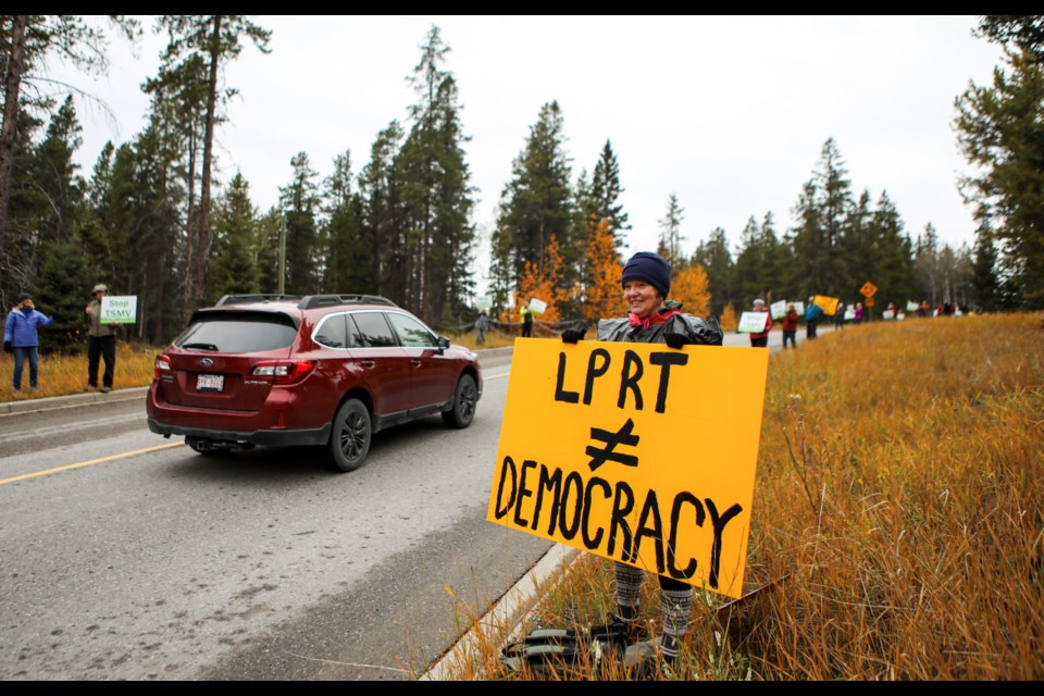 Marie Mclean holds up a sign during a protest about a court decision that paves the way for Three Sisters Mountain Village Properties Limited's development. The rally, at the public roundabout below the Silvertip Golf Course in Canmore on Thursday (Oct. 12), coincided with Premier Danielle Smith’s visit to Canmore. JUNGMIN HAM RMO PHOTO