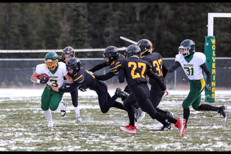 Canmore Wolverines Prince Biado stiff arms Olds Spartans defenders as he runs in a game at Millennium Park in Canmore on Saturday (Oct. 28). JUNGMIN HAM RMO PHOTO