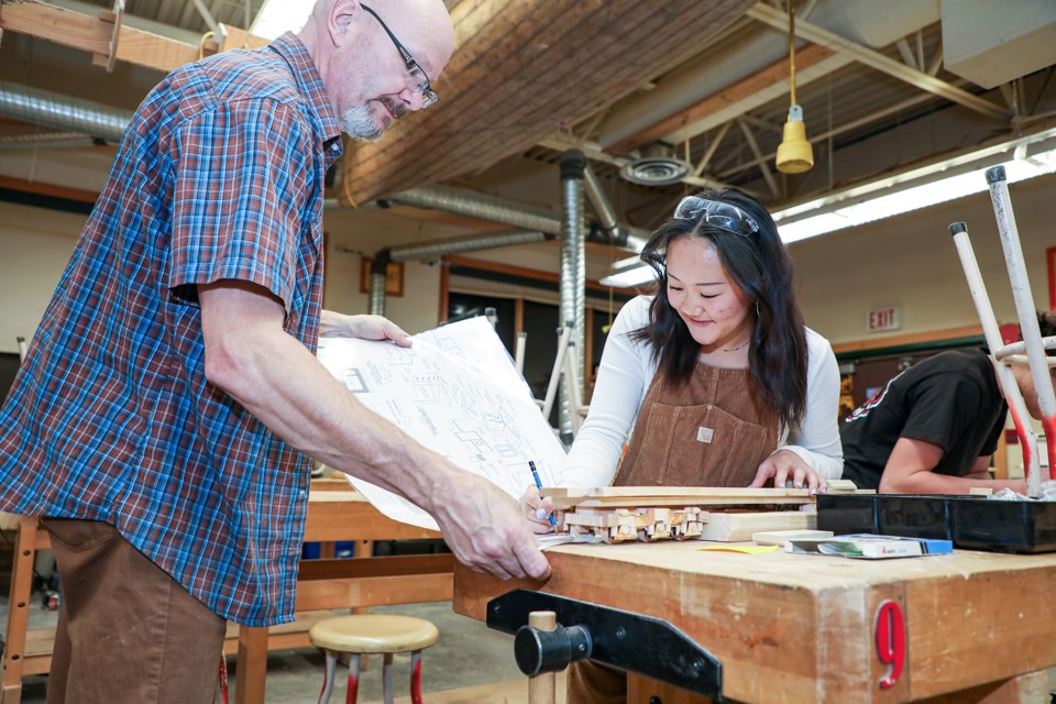 Shop teacher Rob VanderLee, left, helps Grade 11 student Meg Kobayashi with design drawings in the construction course at the Canmore Collegiate High School (CCHS) open house on Wednesday (Nov. 15). JUNGMIN HAM RMO PHOTO