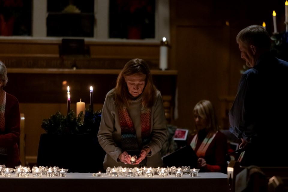 Isabelle Ramsay lights candle in memory of her daughter Merrick, who passed away 12 years ago at the age of 32, at the Community Candlelight Remembrance Service at St. Michael's Anglican Church in Canmore on Thursday (Dec. 7). JUNGMIN HAM RMO PHOTO