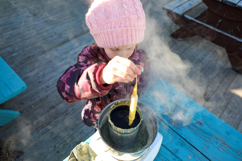 Silver Lens repeatedly dips the thread into beeswax to make candles the traditional way at Candlemas on the Alpenglow School outdoor learning deck in Canmore on Thursday (Feb. 1). JUNGMIN HAM RMO PHOTO 