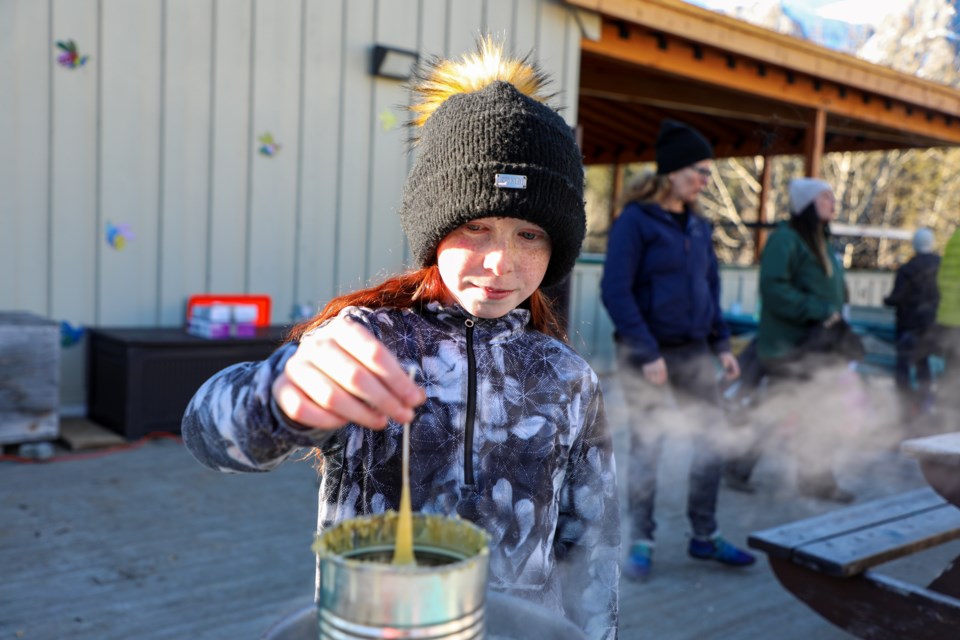 Merlot Lens dips the thread into a hot beeswax to make candles at Candlemas on the Alpenglow School outdoor learning deck in Canmore on Thursday (Feb. 1). JUNGMIN HAM RMO PHOTO 