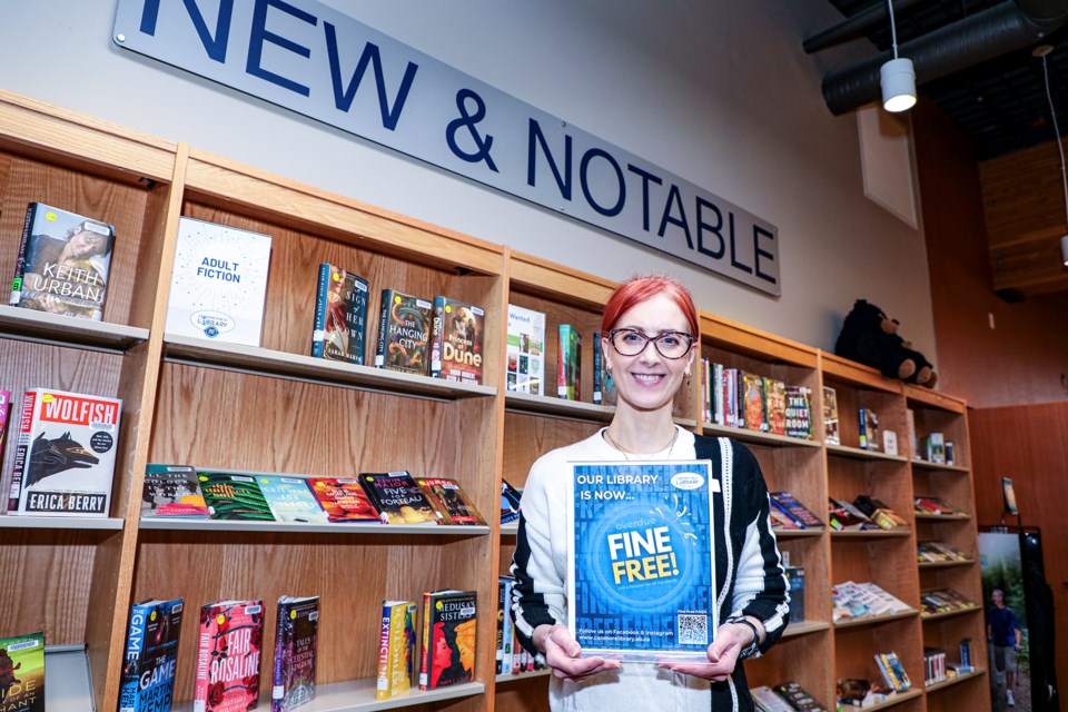 Canmore Public Library director Michelle Preston with a fine free sign at Canmore Public Library on Tuesday (Feb. 20). Canmore Public Library library is no longer charging late fees. JUNGMIN HAM RMO PHOTO