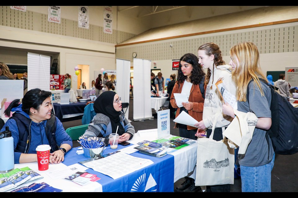 CAREERS program coordinator Gherry Huang, left, and Rahaf Aburashed explain job opportunities at the company to students during the Canadian Rockies Public Schools (CRPS) student hiring fair at Canmore Collegiate High School on Wednesday (March 27). JUNGMIN HAM RMO PHOTO