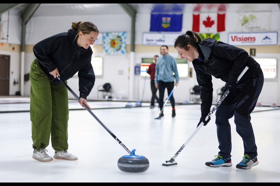 Hannah Arthurs, left, and Jessica Leslie sweep during the curling event with the Canmore Young Adult Network (CYAN) at Canmore Golf & Curling Club on Wednesday (March 27). JUNGMIN HAM RMO PHOTO