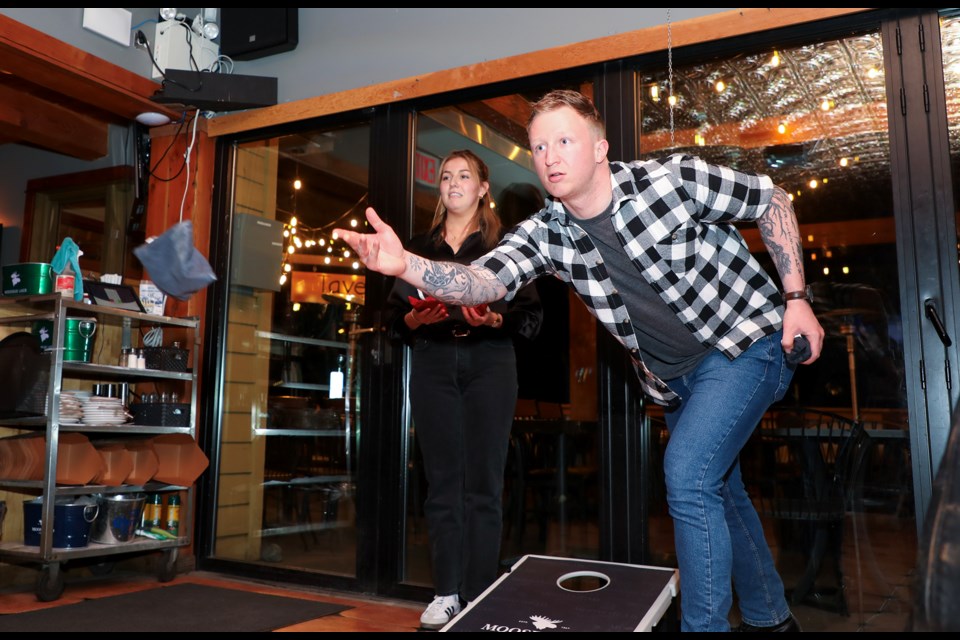 Tomas Podolsky tosses his bag in an underhand motion during the cornhole tournament at Tavern 1883 in Canmore on Thursday (April 25). JUNGMIN HAM RMO PHOTO