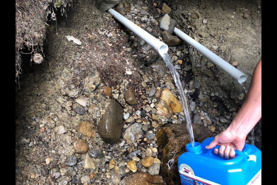 A container is filled with water from the spout at the spring located on Palliser Trail near the Trans-Canada Highway in Canmore. TANYA FOUBERT RMO PHOTO