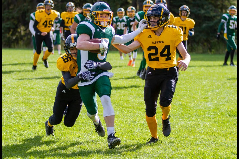 Canmore Wolverines Sam Birch holds off two Olds defenders as he runs for a tochdown in a game at Millennium Park on Saturday (Oct. 5). Evan Buhler RMO FILE PHOTO