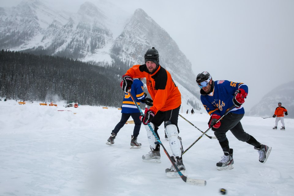 Under a heavy snowfall, Peter McCarthy of Mackenzie Investments passes the puck past the Chiefs Shane Hynes during a round robin game at the 2020 Lake Louise Pond Hockey Classic last February. The Chiefs took home the title for the ninth year out of 11 years the tournament has been operating. EVAN BUHLER RMO PHOTO