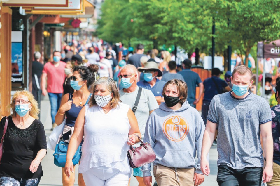 Tourists walk along Banff Avenue wearing face masks on Saturday (Aug. 1). Friday marked the first day the town's mandatory mask by-law took effect. EVAN BUHLER RMO PHOTO